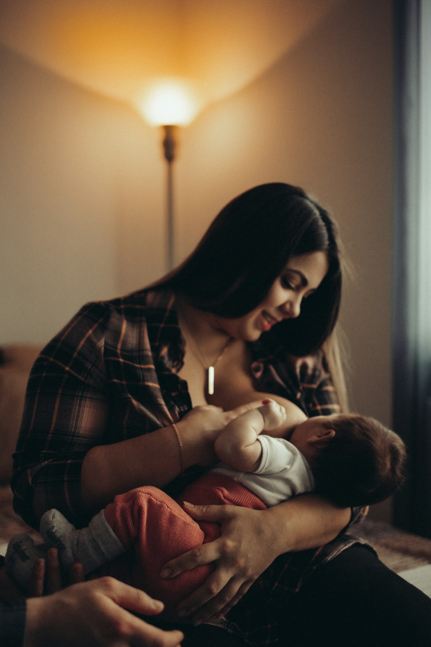 A mother smiling down at her baby while breastfeeding at home.