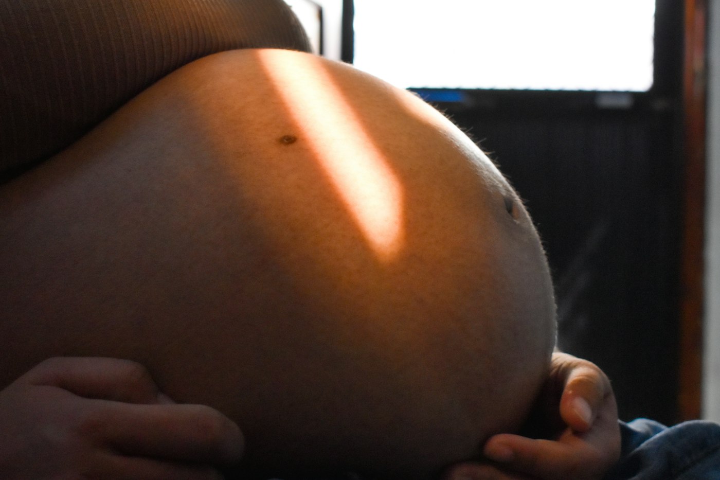 Sunlight falling across a pregnant belly.
