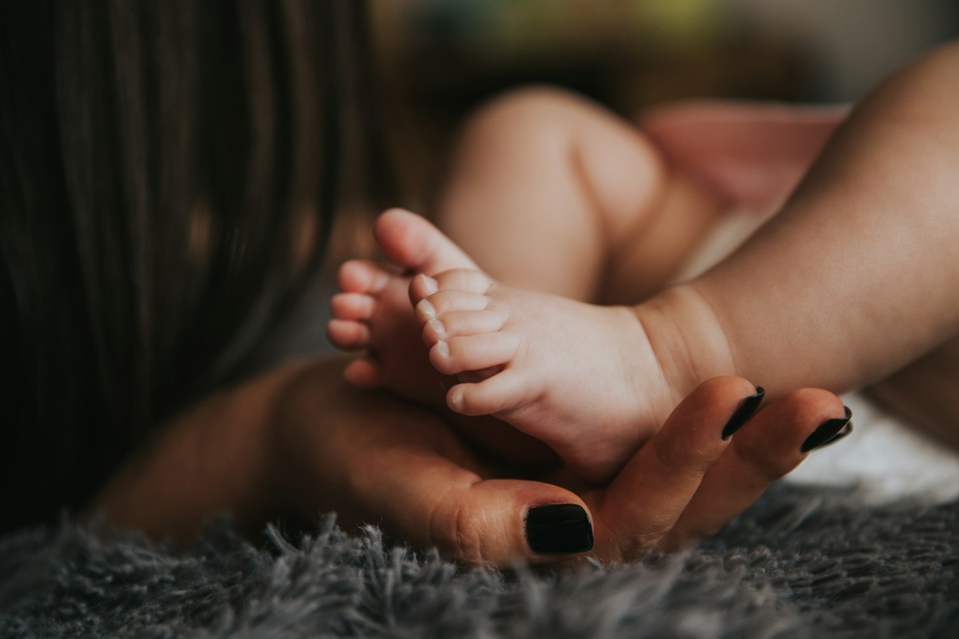 A mother’s hand cradling her baby’s tiny feet.